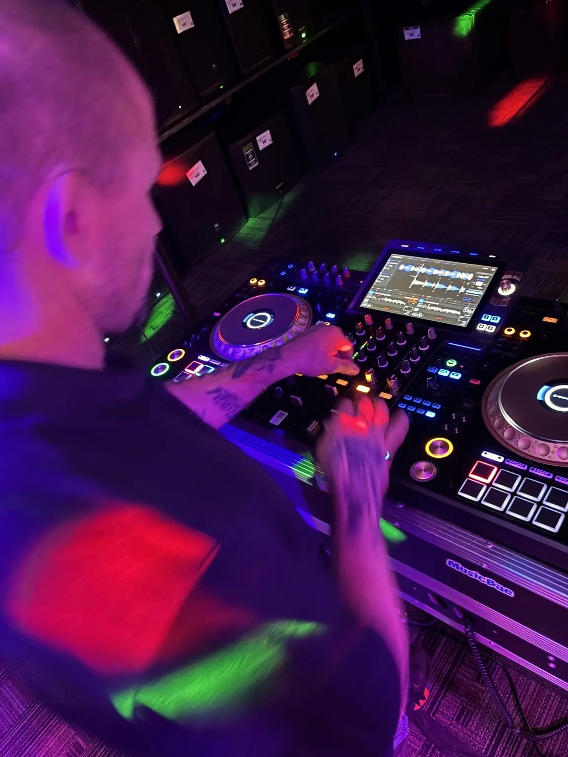 Shane Steven performing on an AlphaTheta XDJ-AZ under red and green lights.